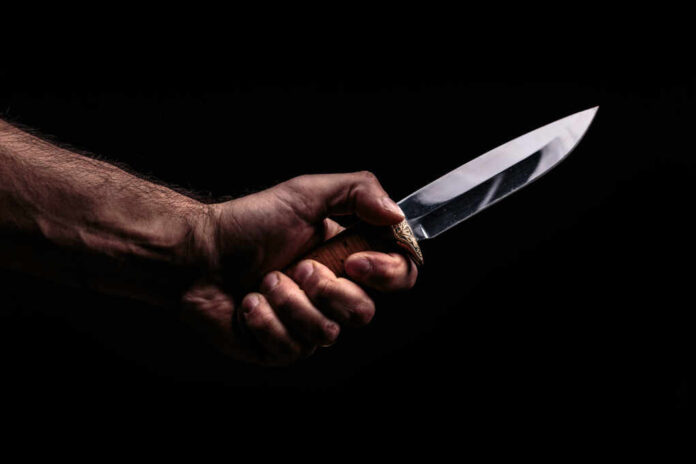 Hunting,Knife,In,Hand,On,Dark,Background