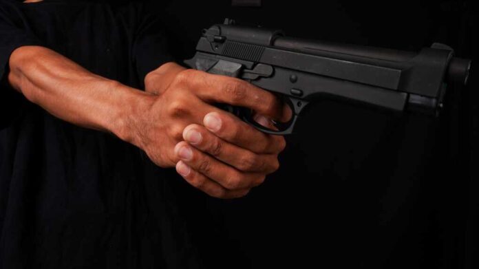 Male,Hand,Holding,A,Gun,On,A,Black,Background.,A