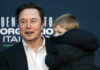 Altman vs. Musk: Orbital Data Centers Feud A man in a black suit holding a child in a coat at a public event