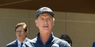 A man speaking at a press conference outdoors with a microphone