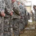 A line of soldiers in military uniforms standing outdoors in formation