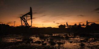 Silhouette of oil pumps against a sunset sky
