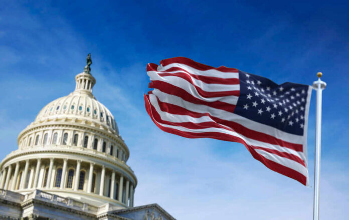 American flag waving in front of the U.S. Capitol building under a clear blue sky
