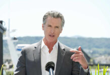 Newsom’s Gas Price Spin Faces Industry Fury A man in a suit speaking at a podium with a microphone outdoors