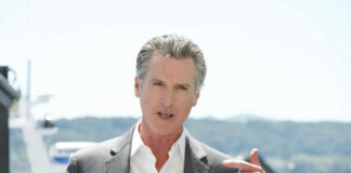 A man in a suit speaking at a podium with a microphone outdoors