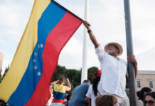 U.S. Military Action Transforms Venezuela Overnight Man holding a Venezuelan flag during a protest