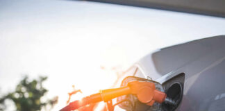 A fuel nozzle inserted into a cars gas tank during sunset