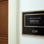 Sign for the Committee on the Judiciary outside a room with wooden doors