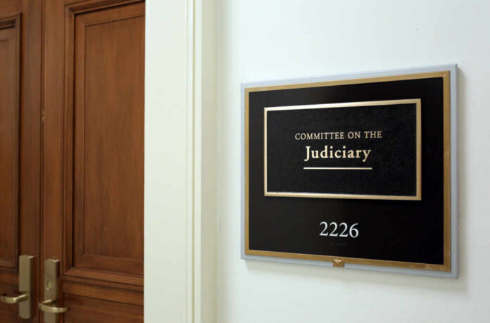 Sign for the Committee on the Judiciary outside a room with wooden doors