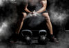 Athlete preparing to lift kettlebells in a gym with chalk dust in the air
