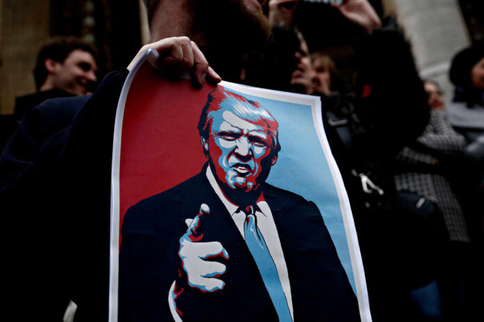 shutterstock_1045773619.jpg A person holding a protest sign featuring a stylized illustration of a man with a serious expression