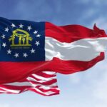 STUNNING Twist in Georgia Senate Race Georgia state flag and American flag waving against a blue sky