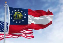 Georgia state flag and American flag waving against a blue sky