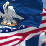 Close-up of the Louisiana state flag with an American flag in the background