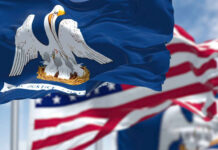 Close-up of the Louisiana state flag with an American flag in the background