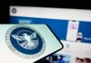 Close-up of a mobile device displaying the TSA logo with a blurred background of a website