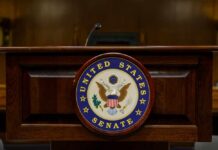 Bipartisan Battle BREWS Over Border Chief Podium with the United States Senate seal in a formal setting