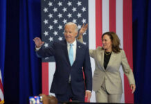 Podcaster’s Explosive Rant: Biden’s DOJ Failure President Biden and Vice President Harris waving at a political event with an American flag backdrop