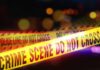 Yellow police tape marking a crime scene with blurred lights in the background