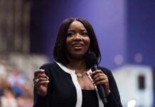 Fugitive Guard in Congresswoman’s Inner Circle A woman speaking into a microphone at a conference