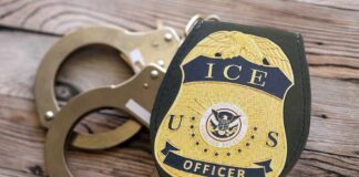 ICE officer badge next to handcuffs on a wooden surface