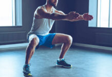 Abolish Back Pain: Ancient Exercise Revealed Man performing a squat exercise in a gym