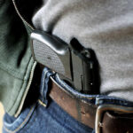 Venezuelan Suspect Grabs Agent’s Gun in Michigan A handgun partially visible in a belt holster worn by a person in casual clothing