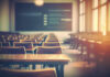 Empty classroom with wooden desks and chairs, illuminated by natural light