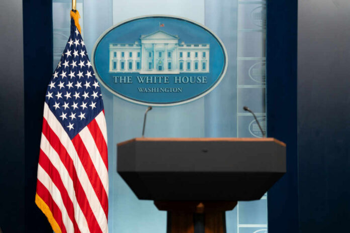 shutterstock2459403981jpg Podium with microphones in front of the White House seal and an American flag