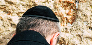 A man wearing a kippah praying at the Western Wall