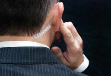 Close-up of a man in a suit with an earpiece, indicating a security role