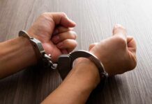Close-up of hands in handcuffs resting on a wooden surface