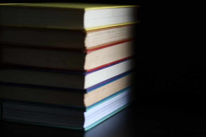 A stack of books with colorful spines against a dark background
