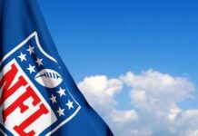 NFL flag waving against a blue sky with clouds