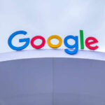 Colorful Google logo displayed on a modern structure against a cloudy sky