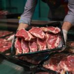 A butcher holding a tray of fresh meat cuts
