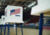 Voting booths with American flags set up in a gymnasium