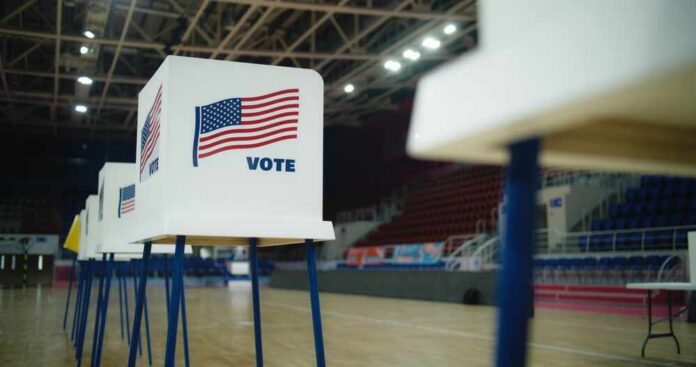 Voting booths with American flags set up in a gymnasium