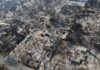 Aerial view of a neighborhood devastated by wildfire, showing burned structures and debris
