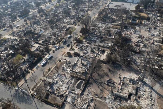Aerial view of a neighborhood devastated by wildfire, showing burned structures and debris