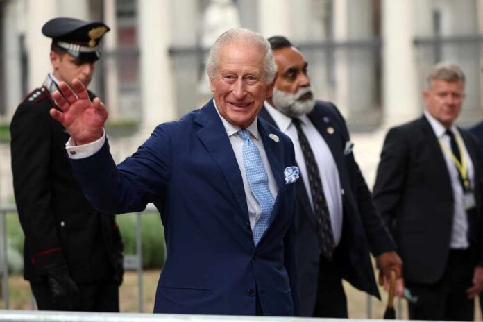 A smiling man in a blue suit waving at the camera