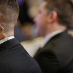Security personnel in formal attire with an earpiece at a business event
