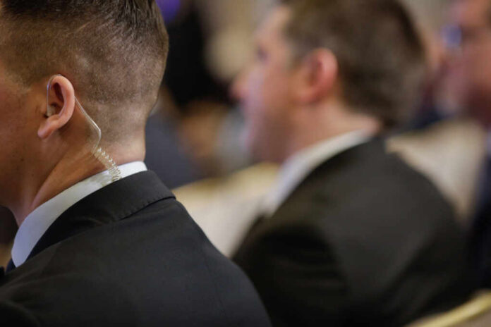Security personnel in formal attire with an earpiece at a business event