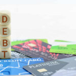 Private Donor Shocks Graduates With Loan Wipeout Stack of wooden blocks spelling DEBT on top of various credit cards