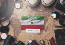 Somaliland flag placed on a vintage map surrounded by travel items