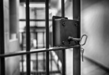Close-up of a jail cell lock with a key hanging