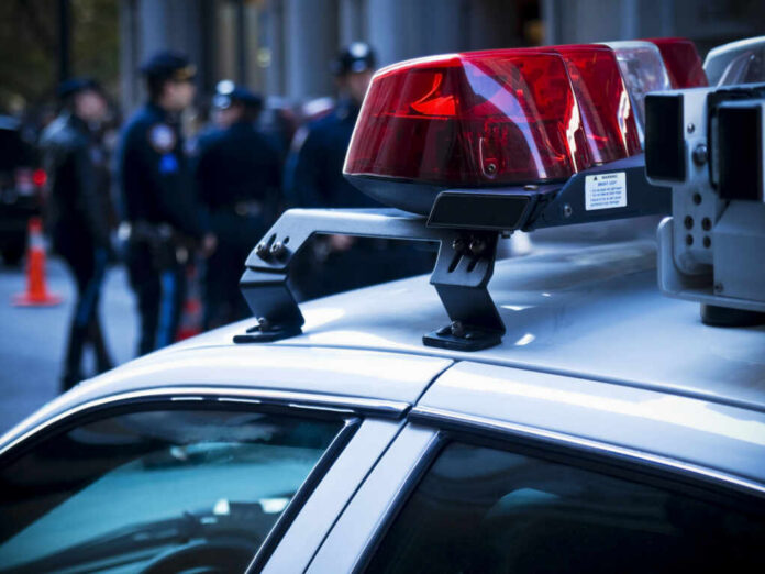 Close-up of a police car with red lights and officers in the background