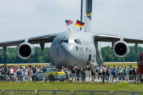 A large military aircraft with flags, surrounded by a crowd at an airshow