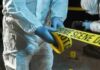 Forensic investigators in protective suits setting up crime scene tape
