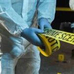 Forensic investigators in protective suits setting up crime scene tape